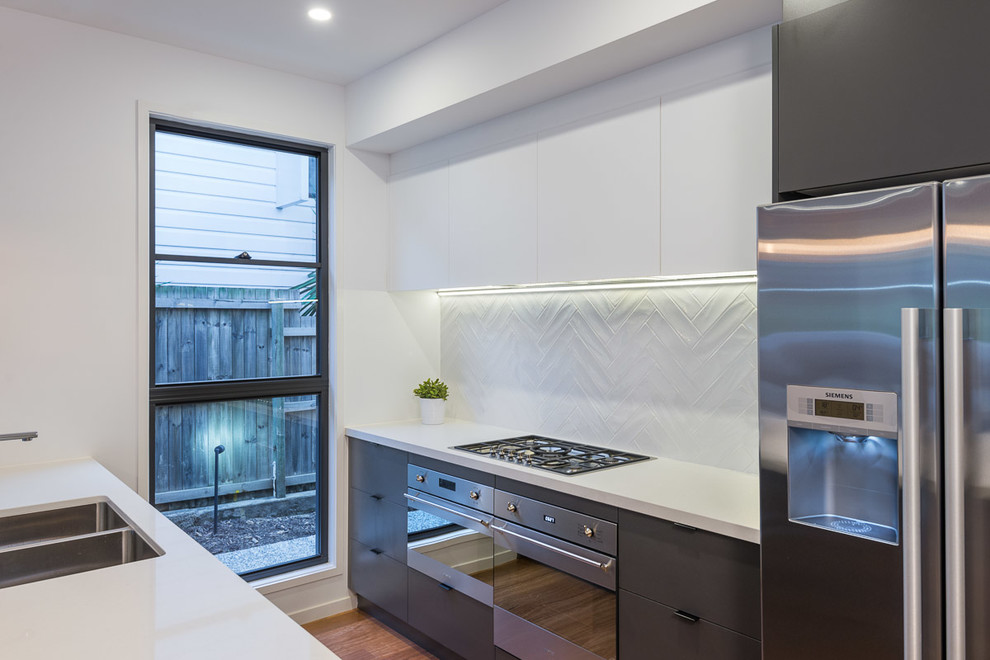 Medium sized contemporary galley kitchen/diner in Brisbane with a double-bowl sink, flat-panel cabinets, grey cabinets, engineered stone countertops, white splashback, ceramic splashback, stainless steel appliances, light hardwood flooring and an island.