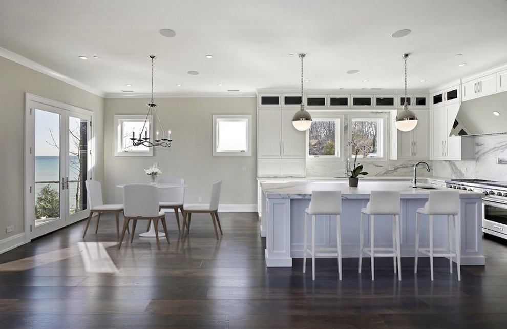 Example of a mid-sized transitional l-shaped dark wood floor and brown floor eat-in kitchen design in Chicago with an undermount sink, shaker cabinets, white cabinets, marble countertops, white backsplash, marble backsplash, stainless steel appliances and an island