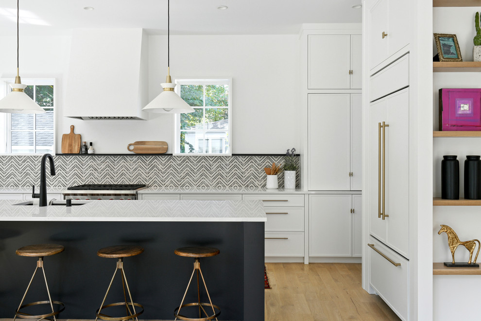 ミネアポリスにある広いトランジショナルスタイルのおしゃれなキッチン (ドロップインシンク、黒いキャビネット、黒いキッチンパネル、シルバーの調理設備、淡色無垢フローリング、白いキッチンカウンター) の写真