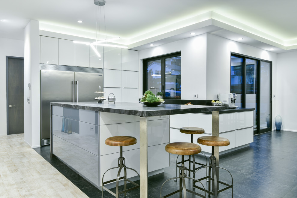 Photo of a large contemporary single-wall open plan kitchen in San Diego with flat-panel cabinets, white cabinets, stainless steel appliances, an island and black floors.