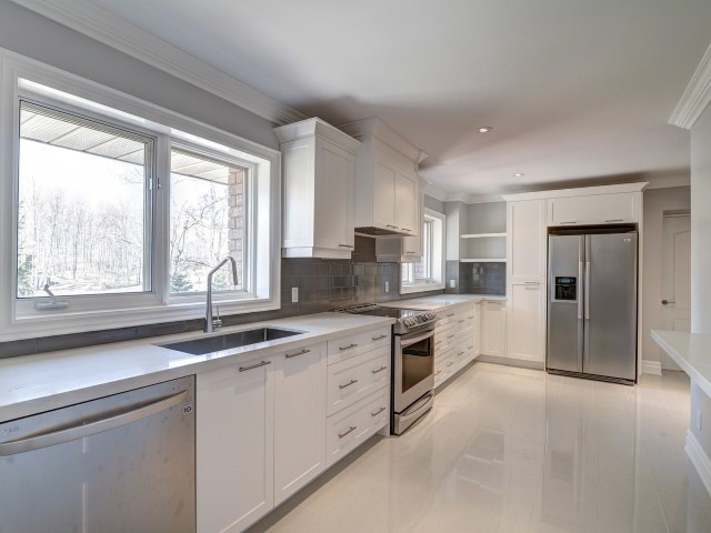 Photo of a medium sized classic l-shaped open plan kitchen in Toronto with a submerged sink, shaker cabinets, white cabinets, engineered stone countertops, grey splashback, stainless steel appliances, an island, white floors and white worktops.