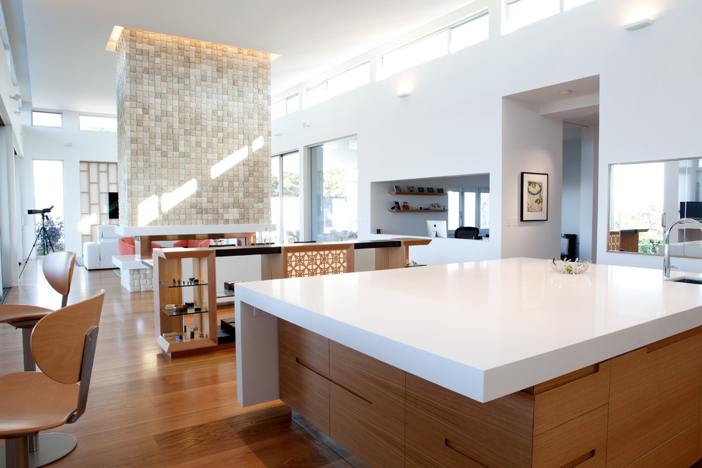 Exemple d'une grande arrière-cuisine moderne en bois clair avec un plan de travail en quartz modifié, une crédence beige et îlot.