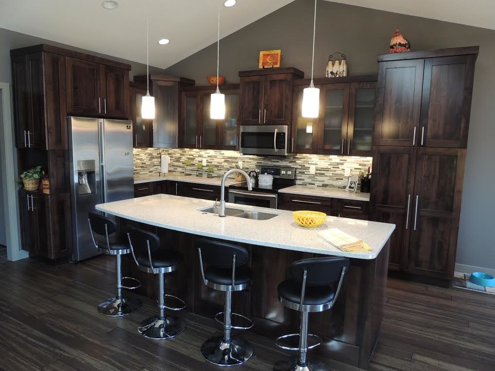 Mid-sized transitional l-shaped medium tone wood floor and brown floor eat-in kitchen photo in Cedar Rapids with a double-bowl sink, shaker cabinets, dark wood cabinets, quartz countertops, beige backsplash, matchstick tile backsplash, stainless steel appliances and an island