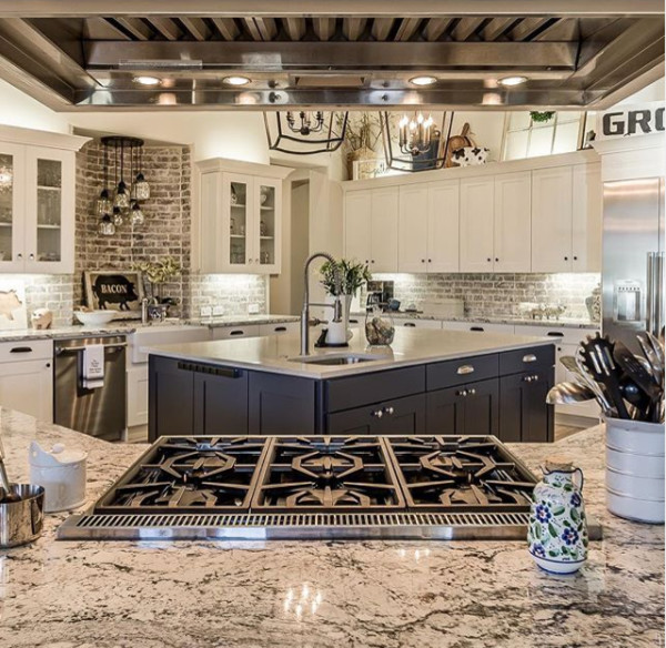 Large minimalist u-shaped light wood floor, brown floor and vaulted ceiling kitchen pantry photo in Dallas with a farmhouse sink, shaker cabinets, white cabinets, granite countertops, gray backsplash, brick backsplash, stainless steel appliances, an island and gray countertops