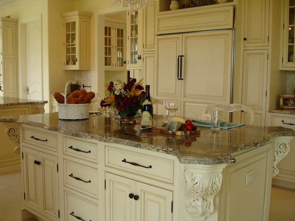 Example of a tuscan galley travertine floor open concept kitchen design in New York with raised-panel cabinets, white cabinets, granite countertops, two islands, an undermount sink, beige backsplash, ceramic backsplash and stainless steel appliances