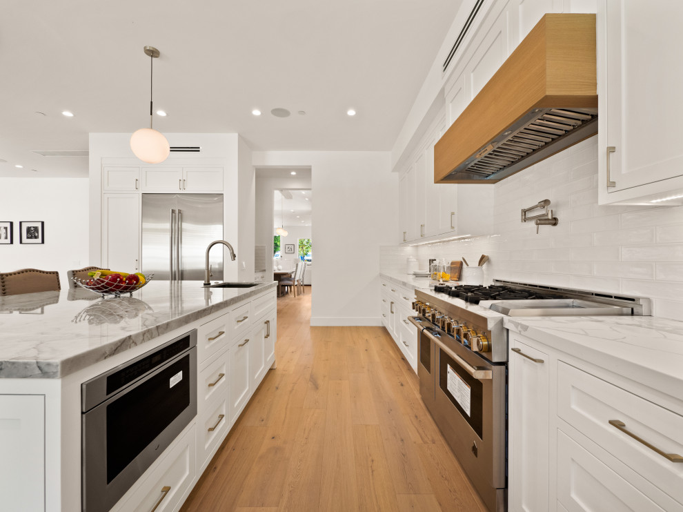 Exempel på ett stort lantligt flerfärgad flerfärgat kök, med en undermonterad diskho, skåp i shakerstil, vita skåp, marmorbänkskiva, vitt stänkskydd, ljust trägolv och en köksö