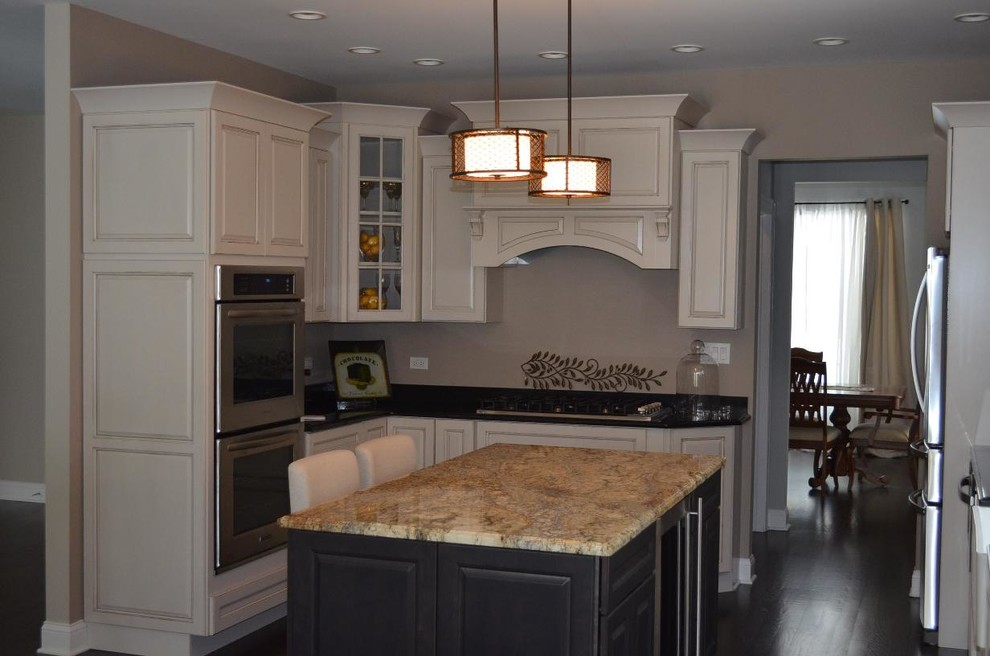 Large traditional u-shaped open plan kitchen in Chicago with a belfast sink, recessed-panel cabinets, white cabinets, granite worktops, green splashback, white appliances and dark hardwood flooring.