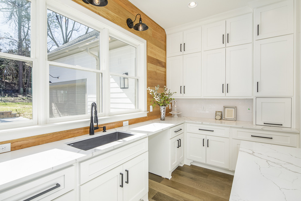 Eat-in kitchen - mid-sized craftsman u-shaped medium tone wood floor and brown floor eat-in kitchen idea in Atlanta with a drop-in sink, white cabinets, marble countertops, white backsplash, subway tile backsplash, stainless steel appliances, an island and white countertops
