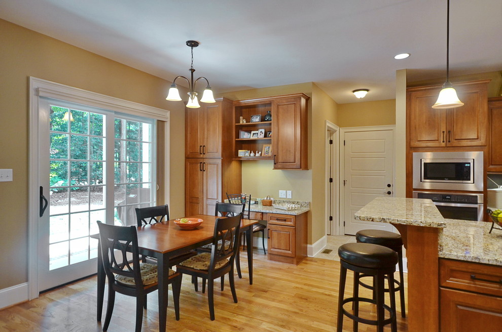 Elegant l-shaped eat-in kitchen photo in Charlotte with raised-panel cabinets, medium tone wood cabinets, granite countertops and stainless steel appliances