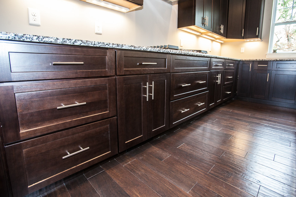 Mid-sized elegant u-shaped dark wood floor open concept kitchen photo in St Louis with a drop-in sink, shaker cabinets, dark wood cabinets, granite countertops, white backsplash, stainless steel appliances and an island