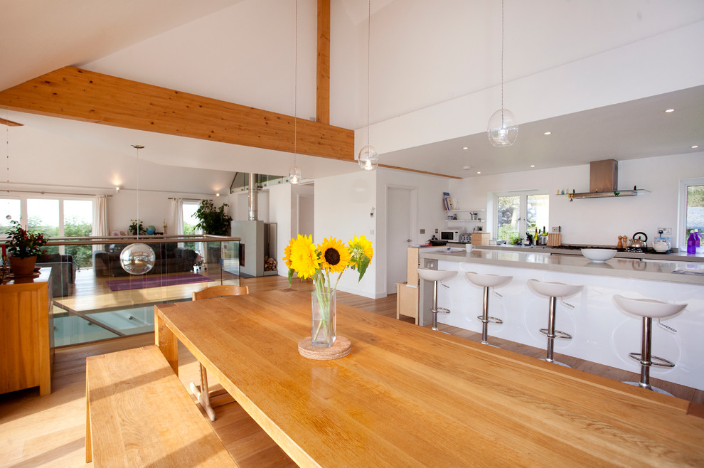 Moderne Wohnküche mit Küchengeräten aus Edelstahl, braunem Holzboden, Kücheninsel und gewölbter Decke in Cornwall