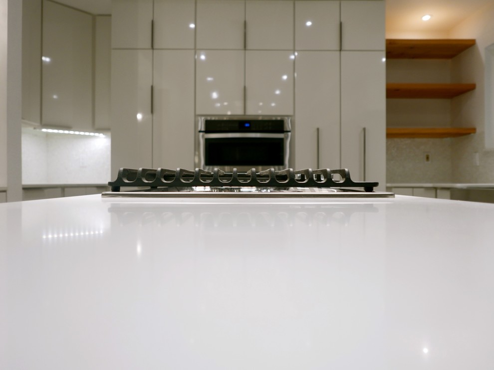 Photo of a modern u-shaped open plan kitchen in Dallas with a single-bowl sink, white cabinets, quartz worktops, white splashback, stone tiled splashback, stainless steel appliances, bamboo flooring and an island.