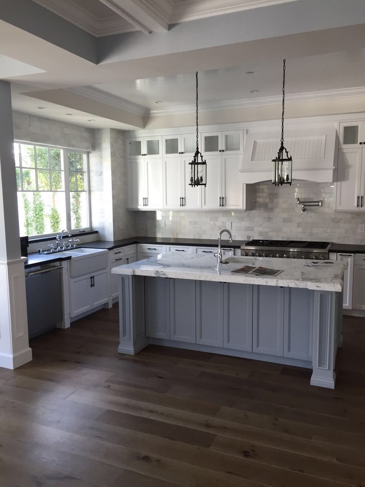 Photo of a large victorian l-shaped kitchen/diner in Los Angeles with a single-bowl sink, shaker cabinets, white cabinets, marble worktops, white splashback, stone tiled splashback, stainless steel appliances, light hardwood flooring and an island.