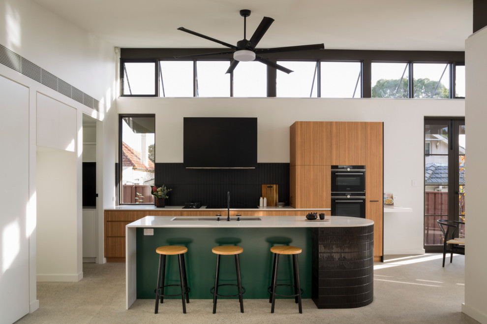 Medium sized contemporary single-wall open plan kitchen in Sydney with a double-bowl sink, recessed-panel cabinets, light wood cabinets, marble worktops, black splashback, ceramic splashback, black appliances, concrete flooring, an island, grey floors and white worktops.