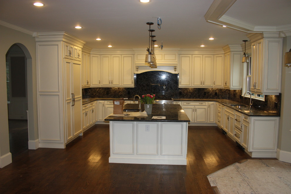 Bild på ett stort vintage kök, med granitbänkskiva, rostfria vitvaror, mörkt trägolv, en köksö, en rustik diskho, luckor med profilerade fronter, vita skåp, svart stänkskydd och stänkskydd i keramik