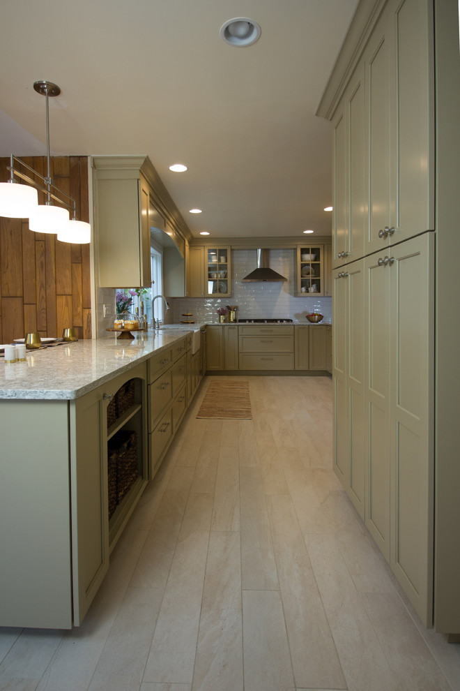 This is an example of a large traditional galley kitchen/diner in New York with a belfast sink, glass-front cabinets, beige cabinets, white splashback, metro tiled splashback, stainless steel appliances, light hardwood flooring and a breakfast bar.
