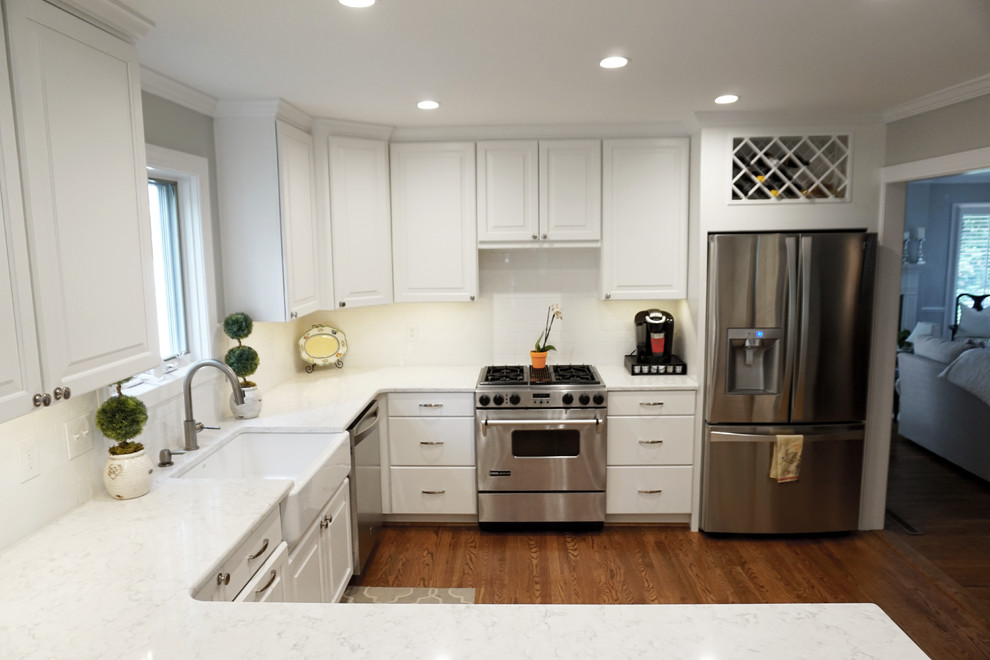 Mid-sized country u-shaped medium tone wood floor eat-in kitchen photo in Charlotte with a farmhouse sink, shaker cabinets, white cabinets, quartzite countertops, white backsplash, ceramic backsplash, stainless steel appliances and a peninsula