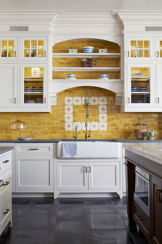 Exempel på ett stort lantligt kök, med en rustik diskho, luckor med infälld panel, marmorbänkskiva, gult stänkskydd, stänkskydd i keramik, kalkstensgolv, en köksö, rostfria vitvaror, vita skåp och svart golv