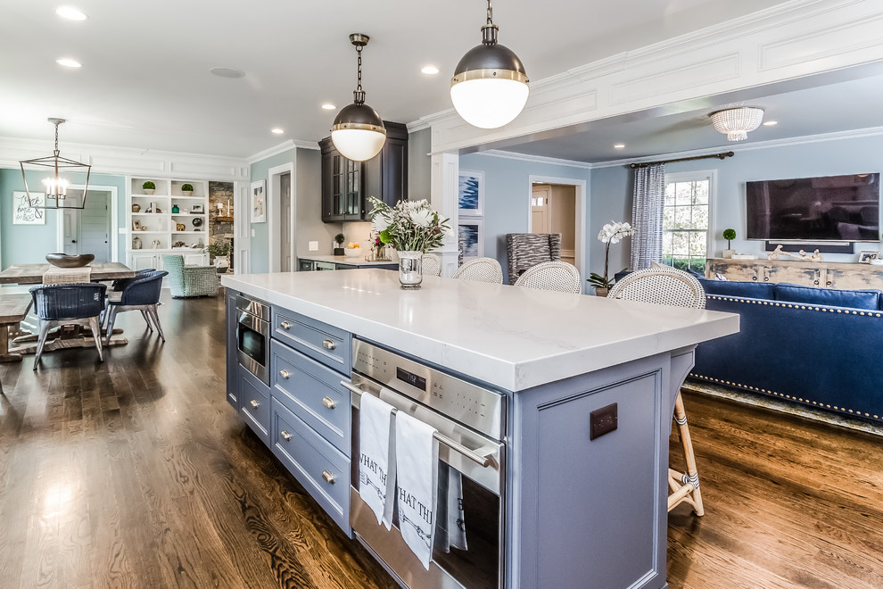 Example of a large classic l-shaped dark wood floor and brown floor eat-in kitchen design in New York with a farmhouse sink, recessed-panel cabinets, white cabinets, marble countertops, white backsplash, subway tile backsplash, stainless steel appliances and an island