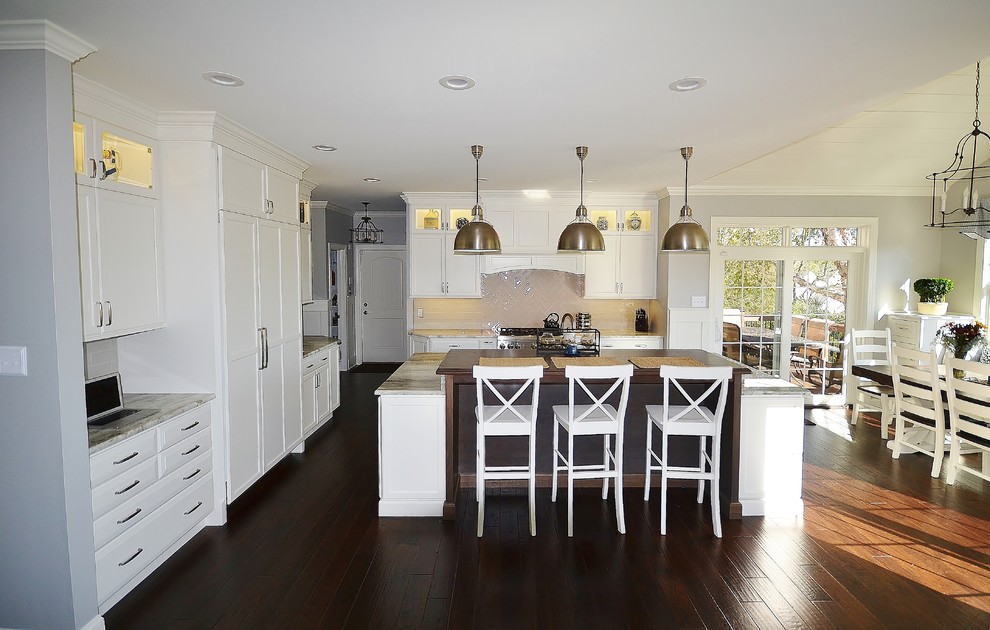 Eat-in kitchen - huge transitional l-shaped dark wood floor and brown floor eat-in kitchen idea in Philadelphia with an undermount sink, raised-panel cabinets, white cabinets, granite countertops, white backsplash, subway tile backsplash, paneled appliances and an island