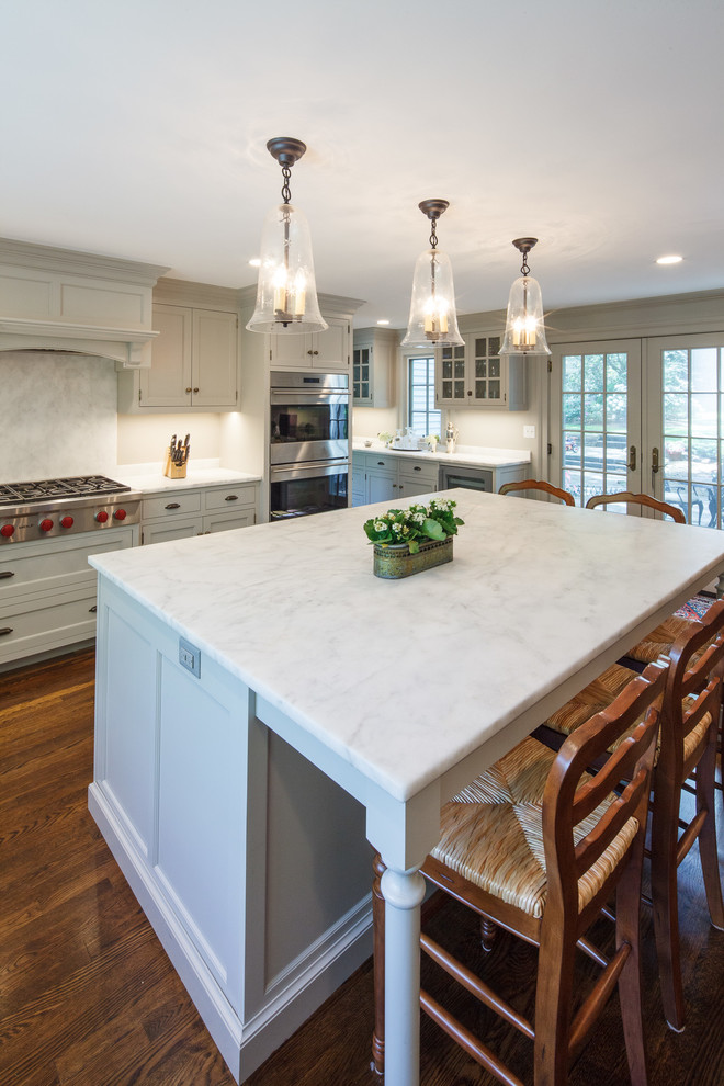 Inspiration for a large transitional l-shaped dark wood floor kitchen remodel in Boston with a single-bowl sink, beaded inset cabinets, gray cabinets, marble countertops, gray backsplash, stone slab backsplash, paneled appliances and an island