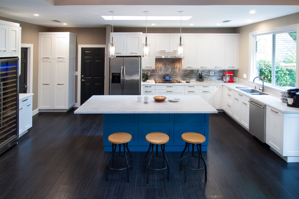 Example of a large trendy l-shaped ceramic tile open concept kitchen design in Sacramento with an undermount sink, shaker cabinets, white cabinets, solid surface countertops, black backsplash, glass sheet backsplash, stainless steel appliances and an island