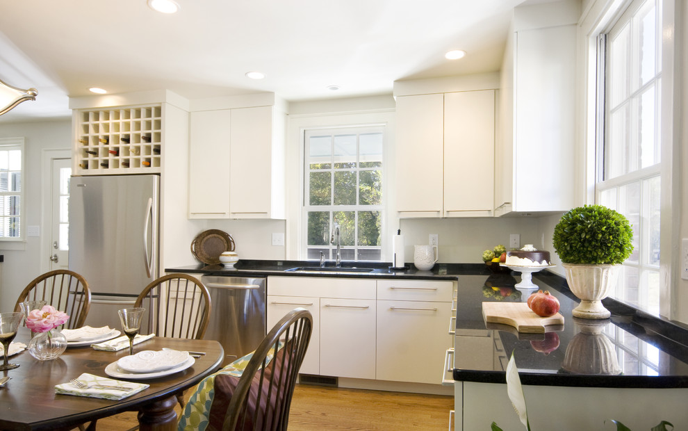 Klassisk inredning av ett kök, med rostfria vitvaror, släta luckor, vita skåp och bänkskiva i kvarts