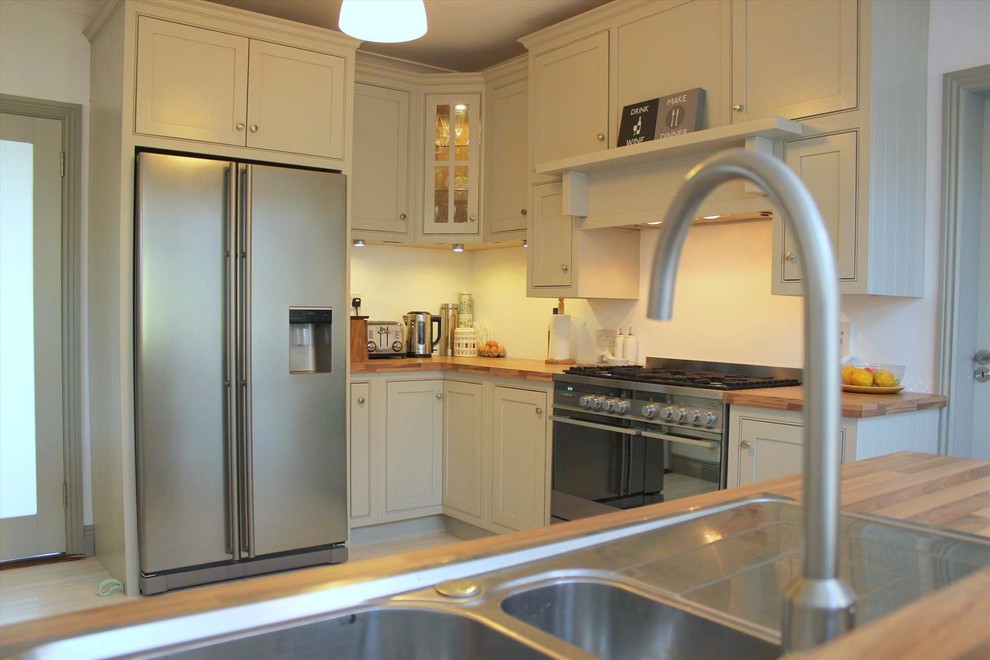 Esempio di una cucina moderna di medie dimensioni con lavello integrato, ante a filo, ante grigie, top in laminato, elettrodomestici in acciaio inossidabile, parquet chiaro e penisola