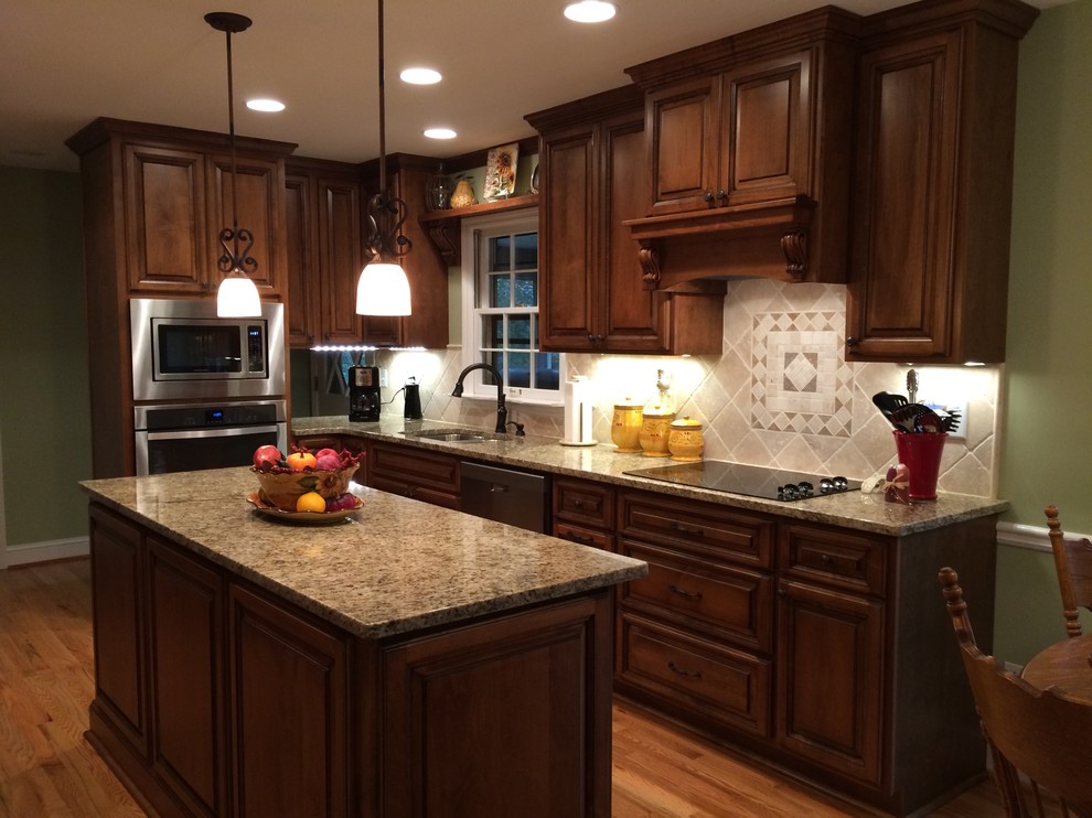 Eat-in kitchen - mid-sized traditional l-shaped medium tone wood floor eat-in kitchen idea in Atlanta with a double-bowl sink, raised-panel cabinets, dark wood cabinets, granite countertops, beige backsplash, stainless steel appliances and an island