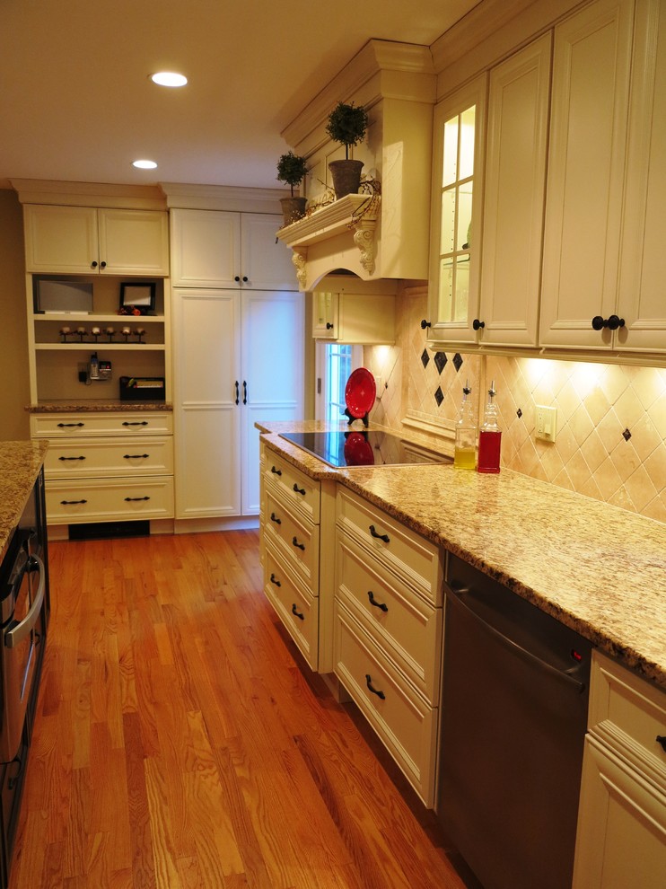 Eat-in kitchen - large traditional l-shaped medium tone wood floor eat-in kitchen idea in Bridgeport with a double-bowl sink, recessed-panel cabinets, beige cabinets, granite countertops, beige backsplash, stone tile backsplash, stainless steel appliances and an island