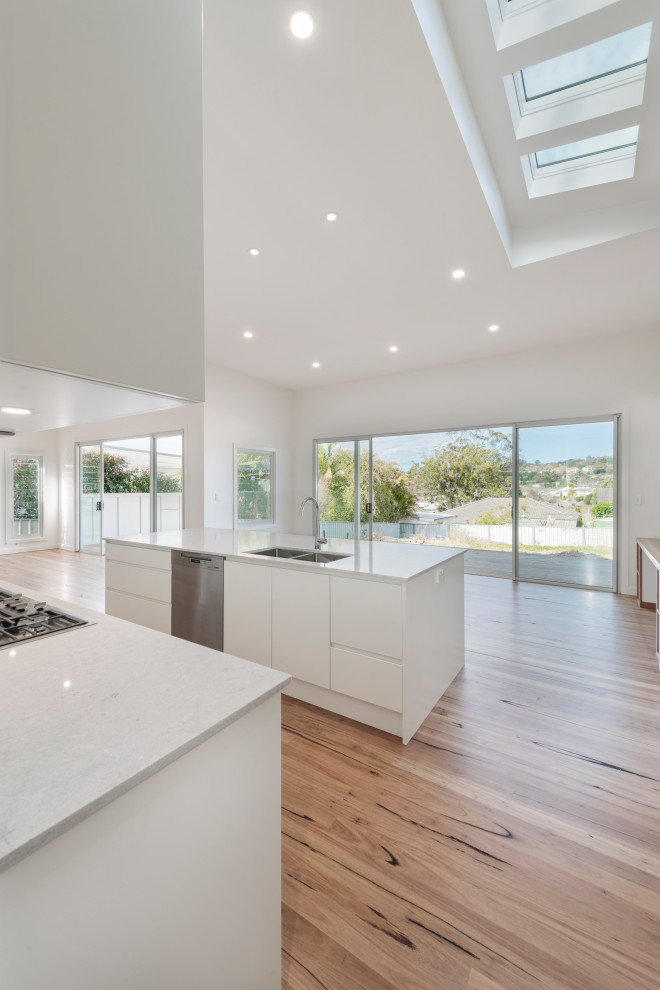 Inspiration for a mid-sized coastal light wood floor kitchen remodel in Newcastle - Maitland with a drop-in sink, solid surface countertops, white backsplash, an island and white countertops