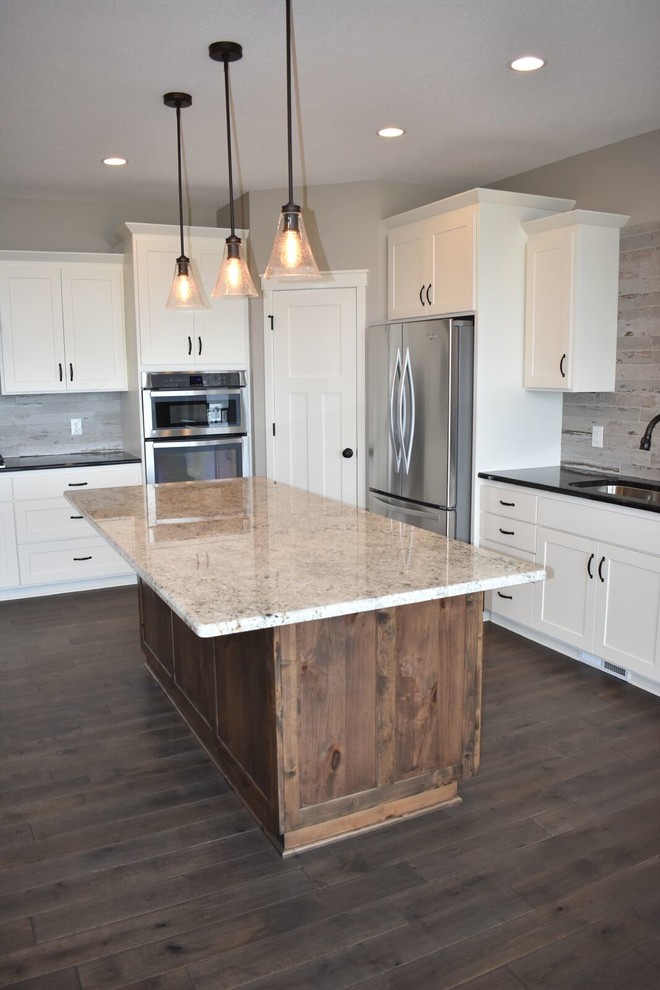 Example of a mid-sized transitional galley dark wood floor and brown floor open concept kitchen design in Minneapolis with shaker cabinets, white cabinets, quartz countertops, gray backsplash, porcelain backsplash and an island