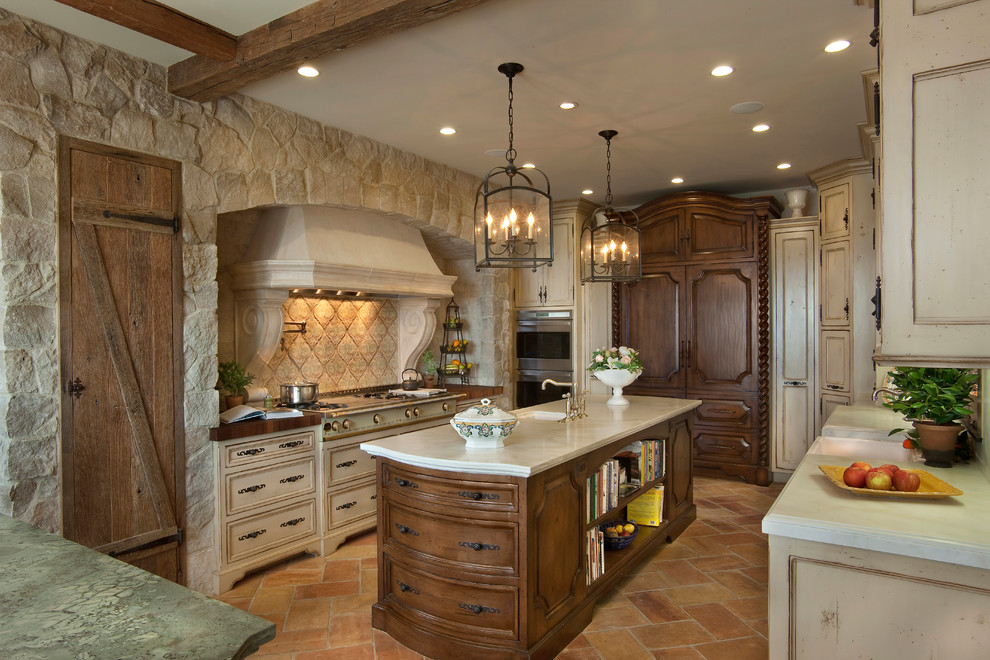 Eat-in kitchen - large mediterranean u-shaped terra-cotta tile and red floor eat-in kitchen idea in San Diego with a farmhouse sink, recessed-panel cabinets, distressed cabinets, marble countertops, white backsplash, stone slab backsplash, paneled appliances and an island