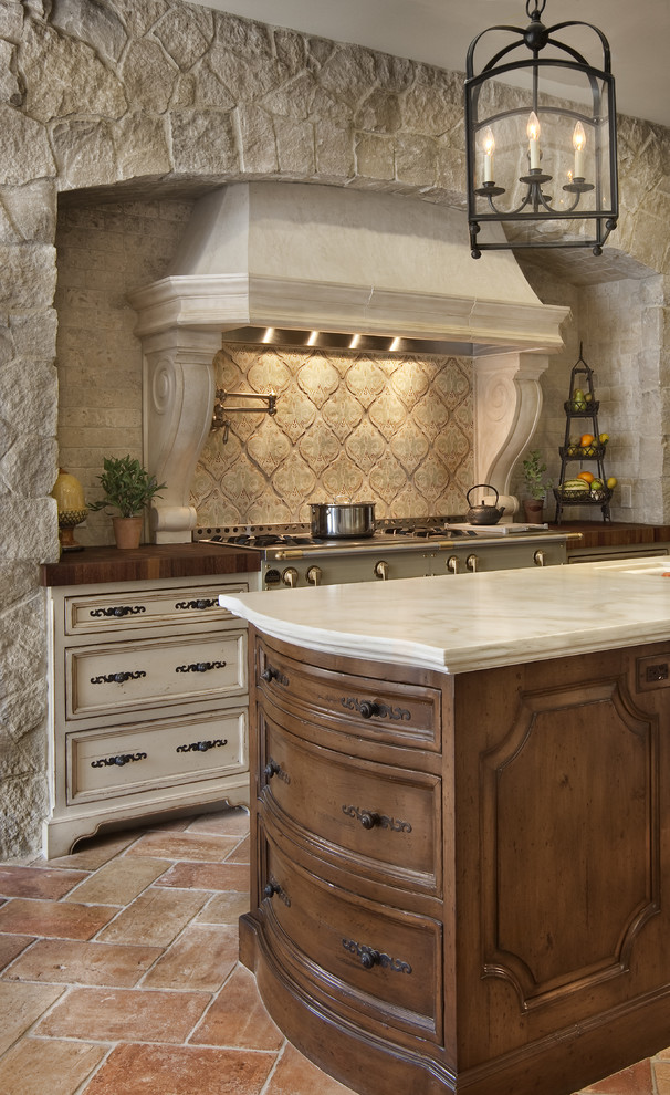 Tuscan kitchen photo in San Diego with terra-cotta backsplash, wood countertops, recessed-panel cabinets, dark wood cabinets and beige backsplash
