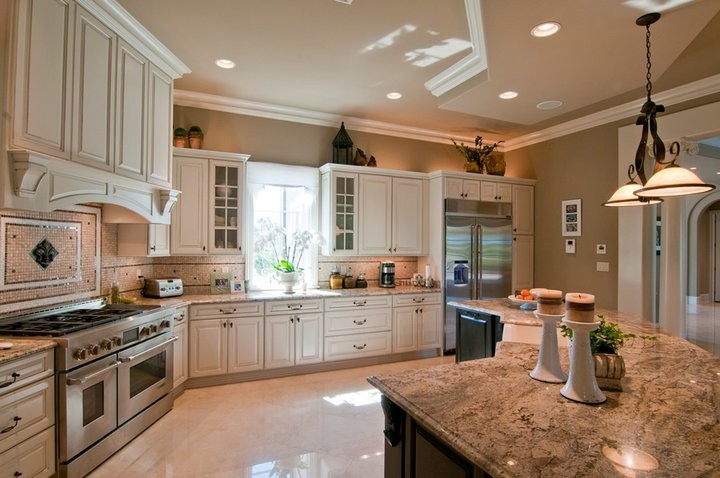 Idéer för att renovera ett stort medelhavsstil brun brunt kök, med en undermonterad diskho, luckor med upphöjd panel, vita skåp, granitbänkskiva, flerfärgad stänkskydd, stänkskydd i mosaik, rostfria vitvaror, klinkergolv i porslin, en köksö och beiget golv