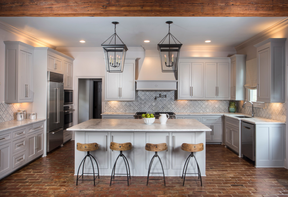 Inspiration for a country u-shaped brick floor kitchen remodel in New Orleans with an undermount sink, shaker cabinets, gray cabinets, marble countertops, white backsplash, stone tile backsplash, stainless steel appliances and an island