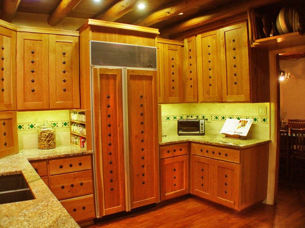 Bild på ett avskilt, mellanstort rustikt u-kök, med en dubbel diskho, skåp i shakerstil, skåp i ljust trä, granitbänkskiva, beige stänkskydd, stänkskydd i travertin, integrerade vitvaror, mörkt trägolv och brunt golv