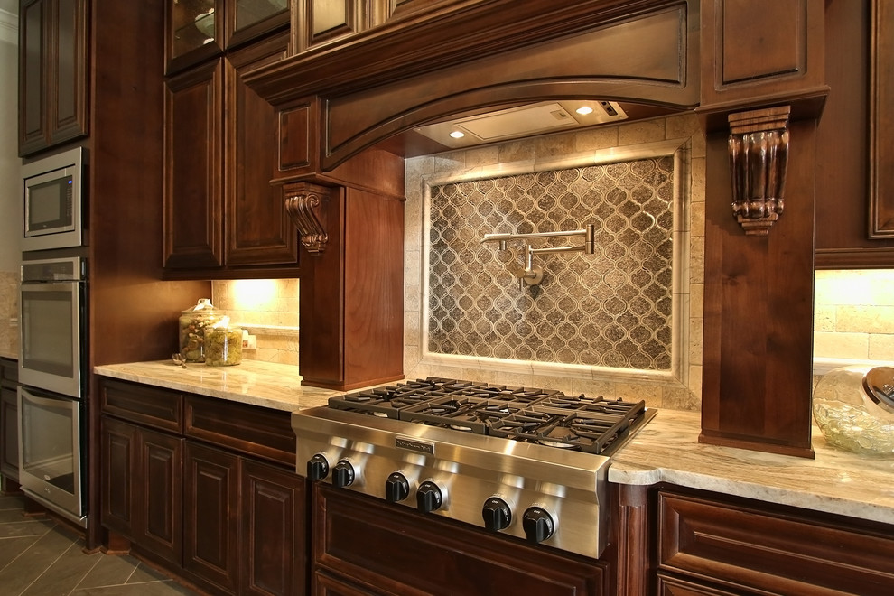 Klassisk inredning av ett mellanstort kök, med en rustik diskho, luckor med upphöjd panel, skåp i mörkt trä, granitbänkskiva, svart stänkskydd, spegel som stänkskydd, rostfria vitvaror, klinkergolv i keramik och en köksö