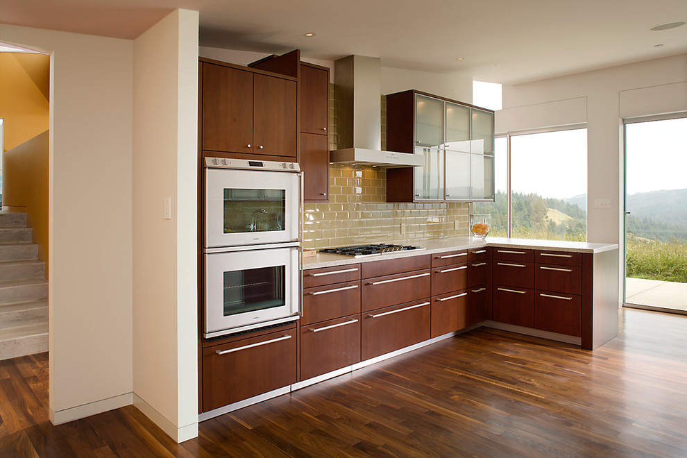 This is an example of a contemporary kitchen in San Francisco with flat-panel cabinets, dark wood cabinets, beige splashback, metro tiled splashback and stainless steel appliances.