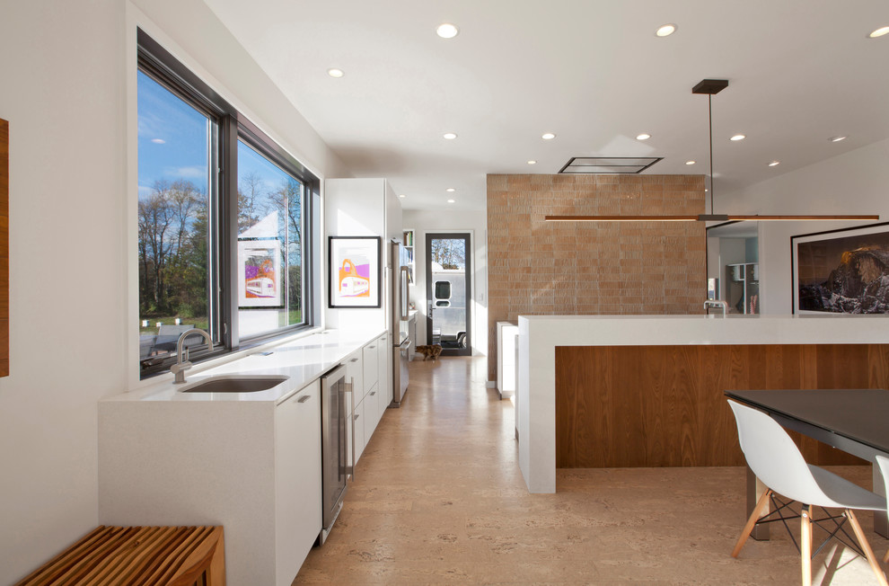 Inredning av ett modernt mellanstort kök, med en undermonterad diskho, släta luckor, vita skåp, bänkskiva i kvarts, orange stänkskydd, stänkskydd i glaskakel, rostfria vitvaror, korkgolv, en köksö och beiget golv