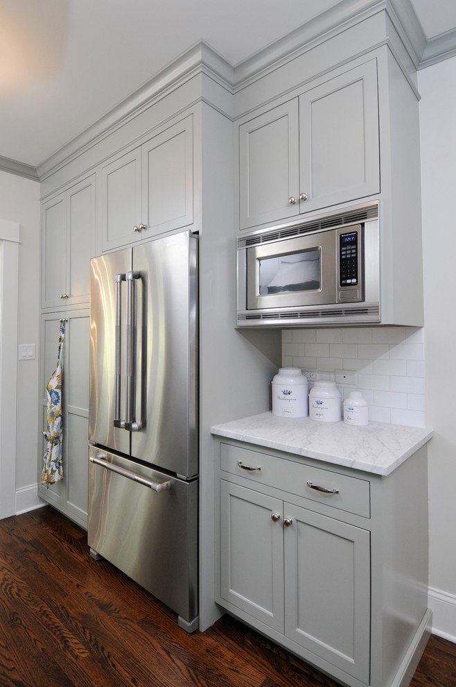 Mid-sized elegant galley dark wood floor enclosed kitchen photo in Chicago with a farmhouse sink, shaker cabinets, marble countertops, white backsplash, subway tile backsplash, stainless steel appliances, no island and gray cabinets