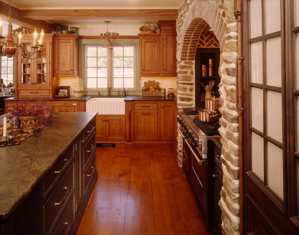 Cette image montre une cuisine ouverte encastrable rustique en L et bois brun de taille moyenne avec un évier de ferme, un placard à porte affleurante, un plan de travail en granite, un sol en bois brun et îlot.