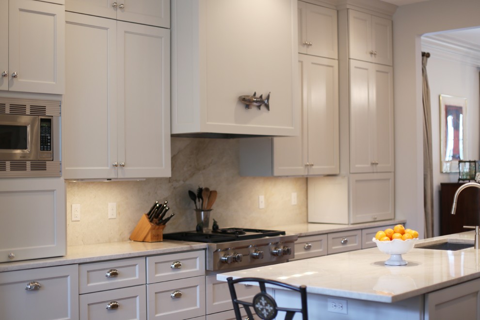 Example of a mid-sized classic galley medium tone wood floor kitchen pantry design in Chicago with an undermount sink, shaker cabinets, beige cabinets, quartzite countertops, beige backsplash, stainless steel appliances and an island