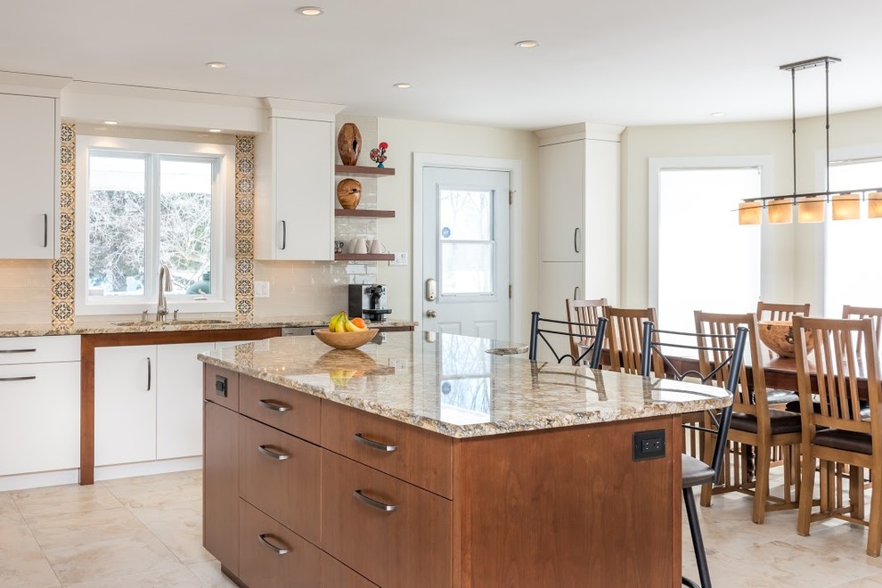 Inspiration for a large transitional l-shaped marble floor eat-in kitchen remodel in Toronto with an undermount sink, flat-panel cabinets, white cabinets, granite countertops, white backsplash, subway tile backsplash, stainless steel appliances and an island