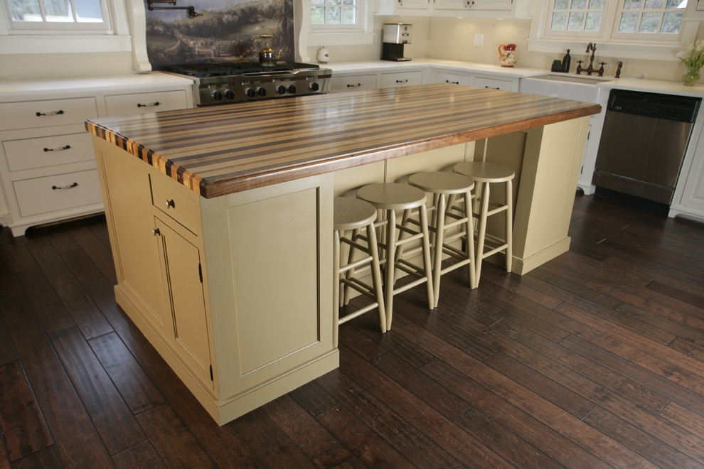 Example of a mid-sized farmhouse l-shaped dark wood floor open concept kitchen design in New York with a farmhouse sink, raised-panel cabinets, white cabinets, solid surface countertops, stainless steel appliances and an island