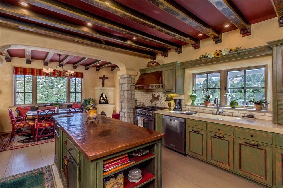 Foto på ett mellanstort amerikanskt kök, med en undermonterad diskho, luckor med upphöjd panel, gröna skåp, bänkskiva i koppar, vitt stänkskydd, stänkskydd i stenkakel, rostfria vitvaror, klinkergolv i keramik, en köksö och beiget golv