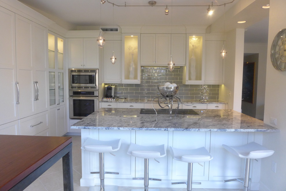 Large transitional l-shaped ceramic tile eat-in kitchen photo in Miami with an undermount sink, recessed-panel cabinets, white cabinets, granite countertops, gray backsplash, subway tile backsplash, stainless steel appliances and an island