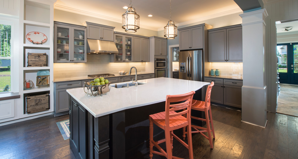 Medium sized classic l-shaped kitchen/diner in Charleston with a double-bowl sink, shaker cabinets, grey cabinets, glass tiled splashback, stainless steel appliances, dark hardwood flooring and an island.