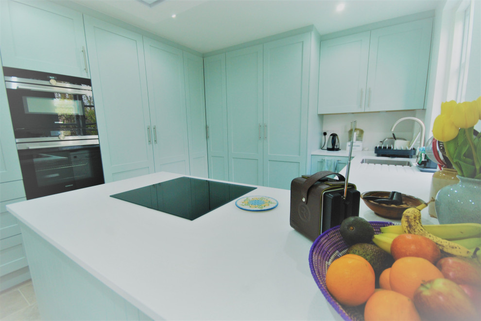 Bild på ett avskilt, mellanstort eklektiskt vit vitt u-kök, med en undermonterad diskho, skåp i shakerstil, blå skåp, bänkskiva i koppar, svarta vitvaror, laminatgolv och grått golv