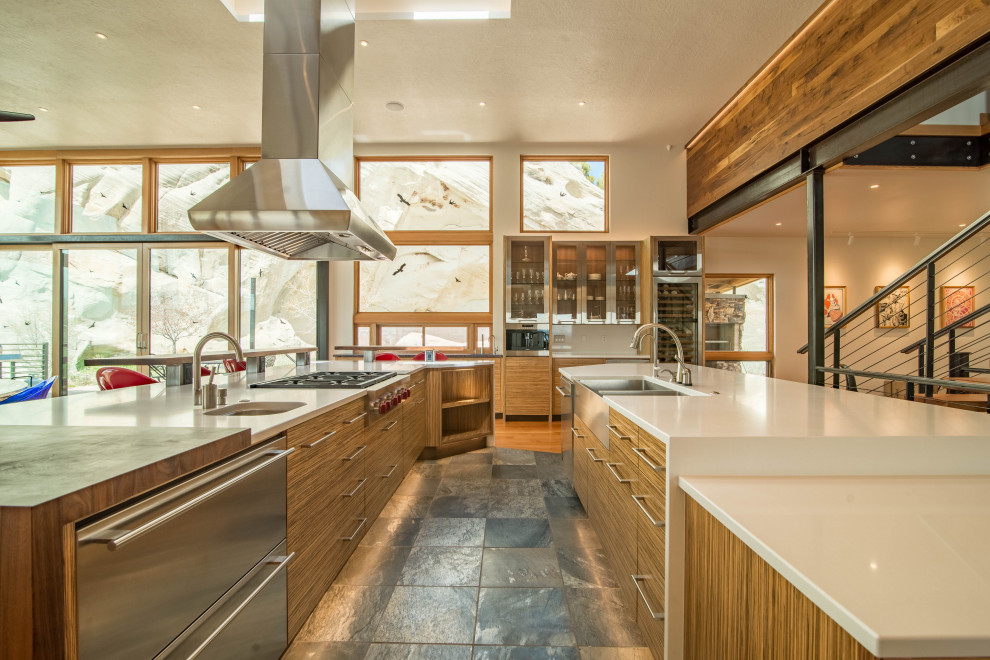 Moderne Küche in L-Form mit Landhausspüle, flächenbündigen Schrankfronten, hellbraunen Holzschränken, Küchengeräten aus Edelstahl, zwei Kücheninseln, grauem Boden und weißer Arbeitsplatte in Salt Lake City